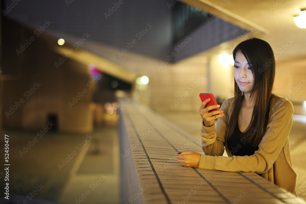 Poster woman using mobile phone in city at night