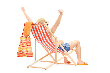 Happy guy enjoying on a beach chair with raised hands