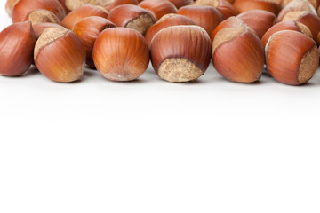 Unbroken hazelnuts on white surface