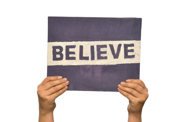 Hand holding up a self painted text Believe isolated on white