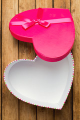 Open heart shape gift box over wooden background