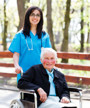 Kind Nurse With Elderly Lady In Wheelchair
