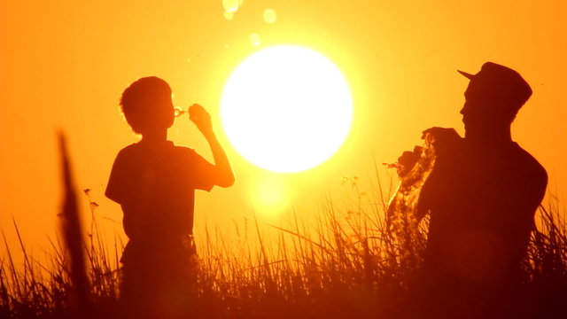 dad and son making soap bubbles in the nature, sunset,