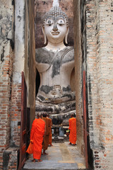 monks worship Buddha statue at Wat Sri Chum in Sukhothai