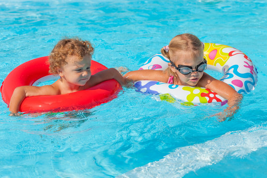  little girl and little boy playing in the pool with rubber ring