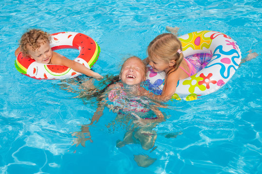 two little girls and little boy playing in the pool
