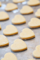 Fototapeta na wymiar Unbaked heart shaped shortbread cookies on baking tray, selectiv