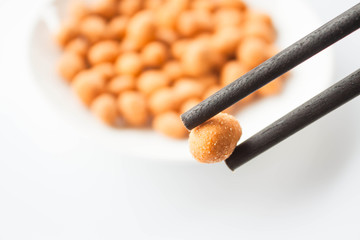 Close up chopstick holding a spicy peanut snack