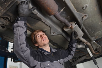 Fototapeta Car mechanic repairs exhaust system obraz