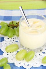 Delicious yogurt in glass with grapes on blue tablecloth