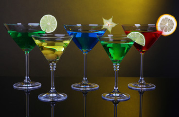 Alcoholic cocktails in martini glasses on dark yellow