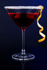 Red cocktail in martini glass on dark blue background