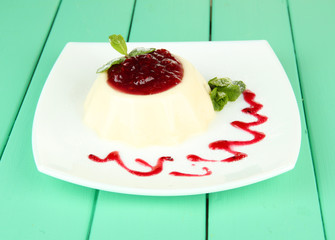 Panna Cotta with raspberry sauce, on color wooden background