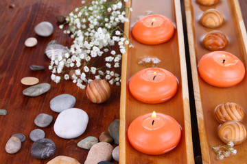 Beautiful candles in water on wooden table close-up