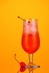 Cherry cocktail with ice on orange background