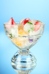 Ice cubes with flowers, fruit pieces and herbs in glass jar,