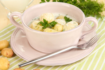 Tender young potatoes with sour cream and herbs in pan