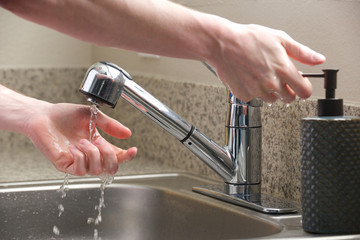 Hands reach for soap at the kitchen sink