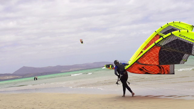Kitesurfer walking on the beach with the kite, super slow motion