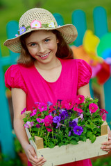 Gardening- lovely girl with petunia flowers in the garden