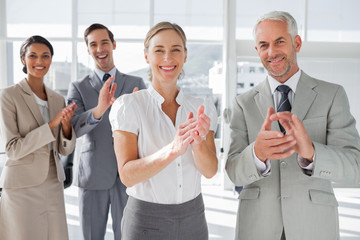Smiling business people applauding together