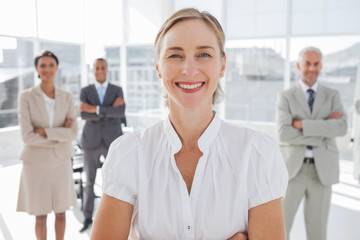 Cheerful businesswoman standing with arms folded