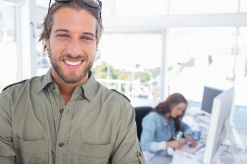 Fototapeta premium Cheerful man in creative office with arms folded