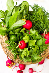 Fresh dil, sorrell and radish in a wicker basket on white wooden