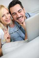 Cheerful couple websurfing on internet with tablet