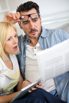 Couple reading news with horrified look