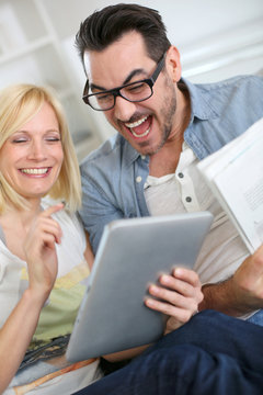 Couple reading news on both internet and paper