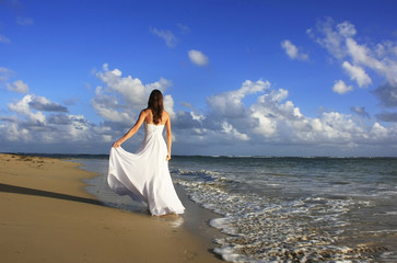 Fototapeta na wymiar Young woman in white dress on a beach