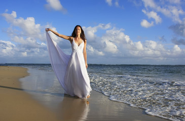 Fototapeta na wymiar Young woman in white dress on a beach