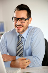 Cheerful businessman working on laptop computer