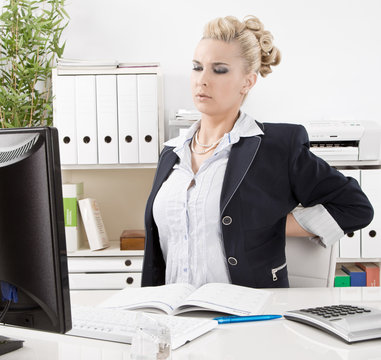 Frau hat R&uuml;ckenschmerzen im B&uuml;ro