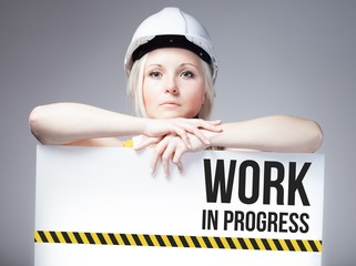 Worker holding work in progress sign on information board