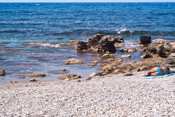 Fototapeta na wymiar Girl sunbathing on the beach of barcarello, Palermo