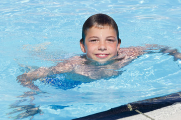 Fototapeta na wymiar Activities on the pool. Cute boy swimming and playing in water i
