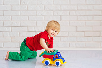 Cute little boy playing with his colorful toy car