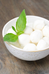 fresh mozzarella and basil in a bowl, close-up vertical