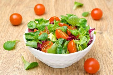 fresh salad and cherry tomatoes in a bowl on wooden background