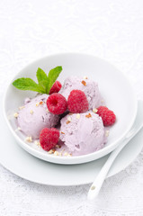 ice cream with fresh raspberries and mint in white bowl