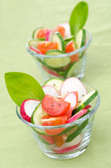 salad of fresh vegetables in portioned glasses on green