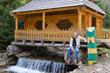 Man sitting at a hut built over a waterfall
