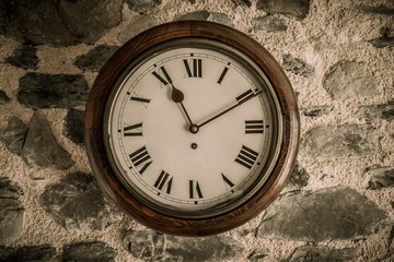 Vintage wooden wall clock on stone wall