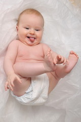 Cute happy 7 month baby girl in diaper lying and playing