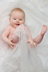 Cute happy 7 month baby girl in diaper lying and playing