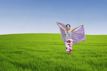 Naklejka na ściany i meble Asian woman running on green field