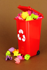 Recycling bin with papers on brown background