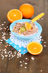 Useful oatmeal in bowl with fruit on wooden table close-up